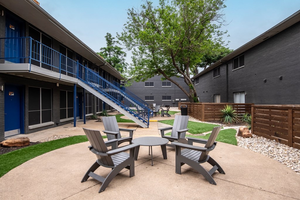 Patio between buildings at Stadium 700 Apartments in Arlington, TX with patio chairs and table on concrete pad