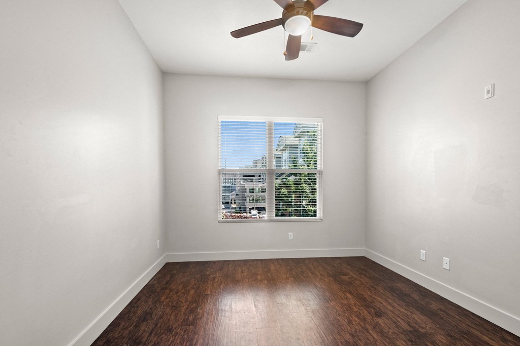 State Street Flats one bedroom apartments in Nashville TN bedroom with a ceiling fan and a window overlooking a cityscape.