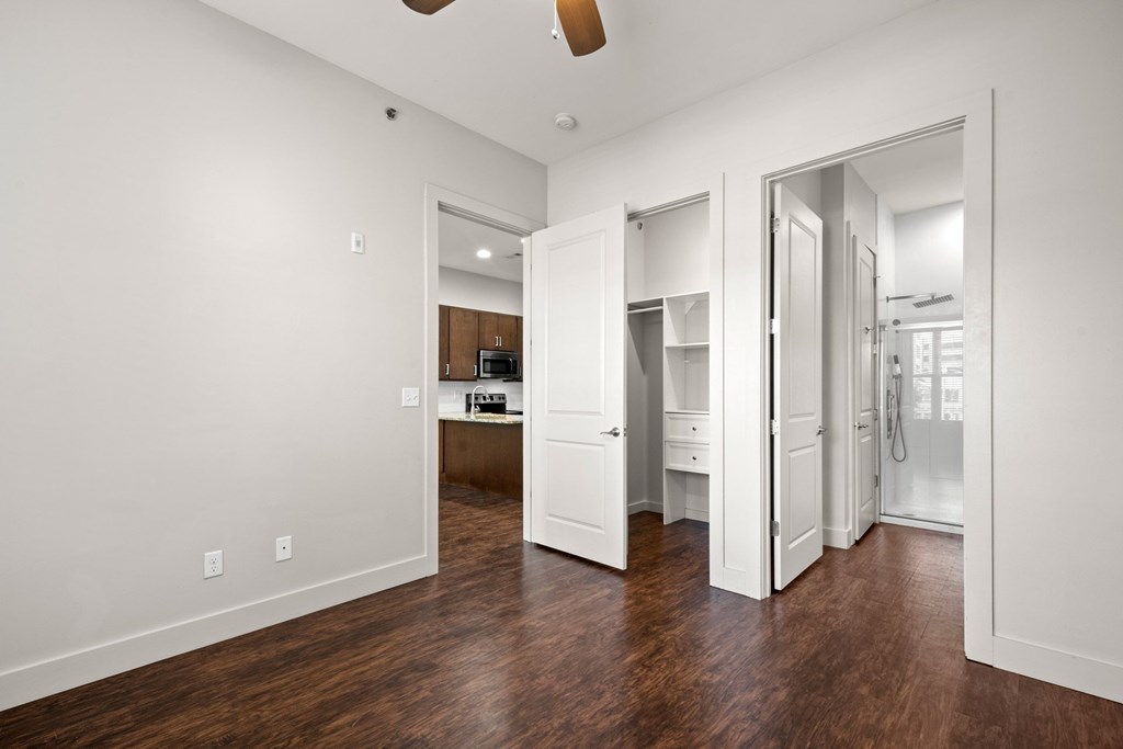 State Street Flats Nashville apt bedroom with white walls and a brown floor.