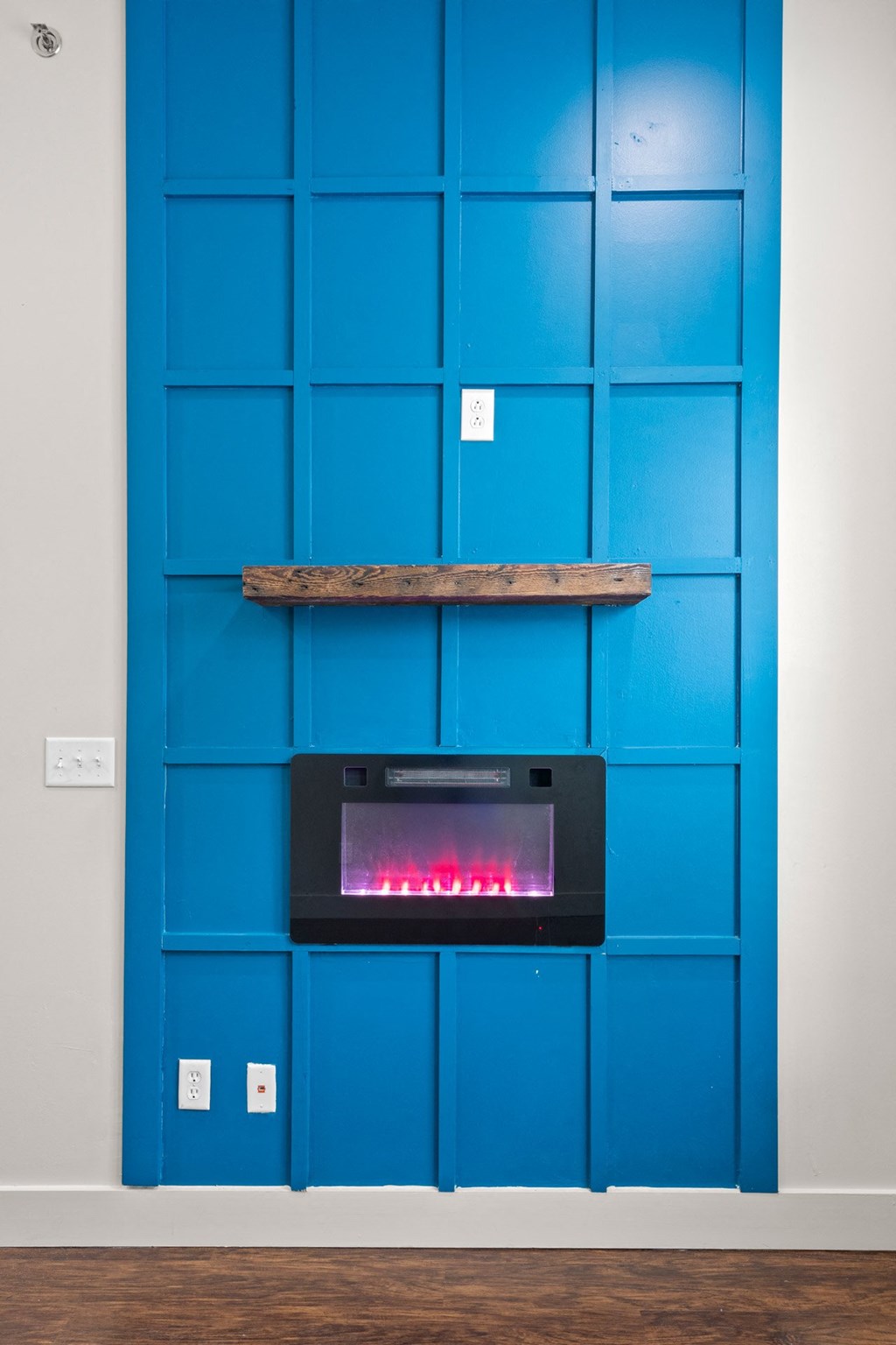 State Street Flats Apartments wall mounted electric fireplace with a blue wall behind it.