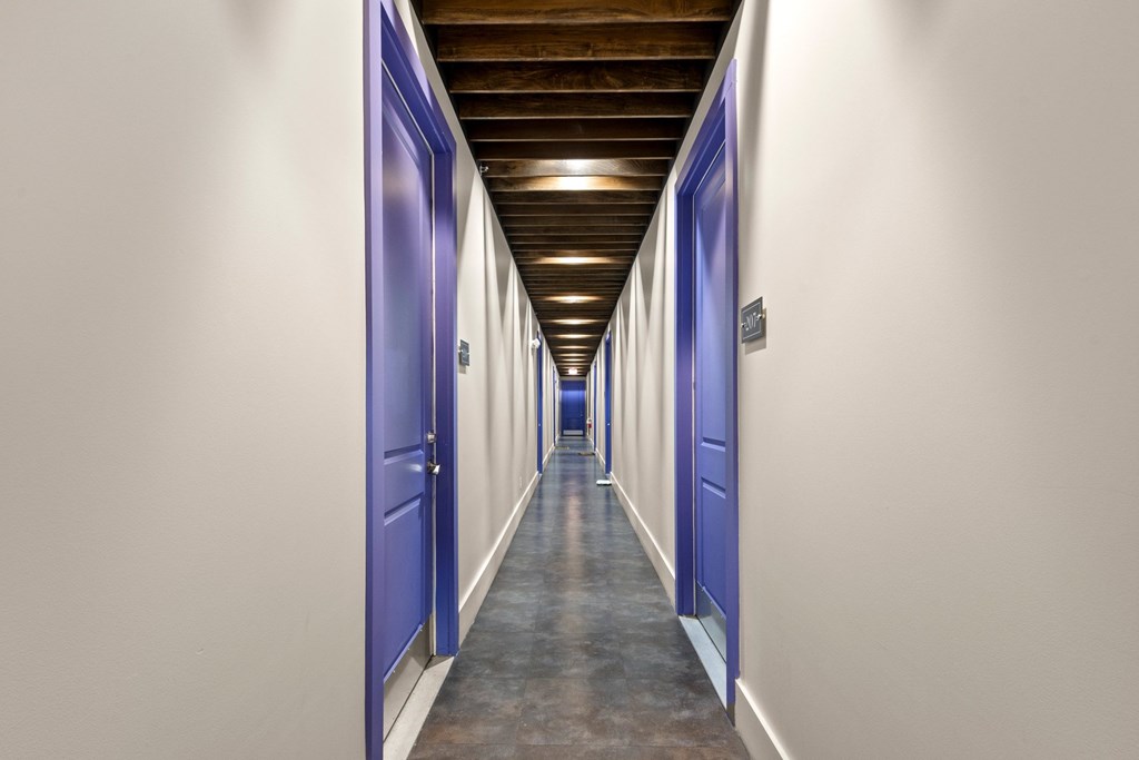State Street Flats one bedroom apartments Nashville long hallway with blue doors and a wooden ceiling.