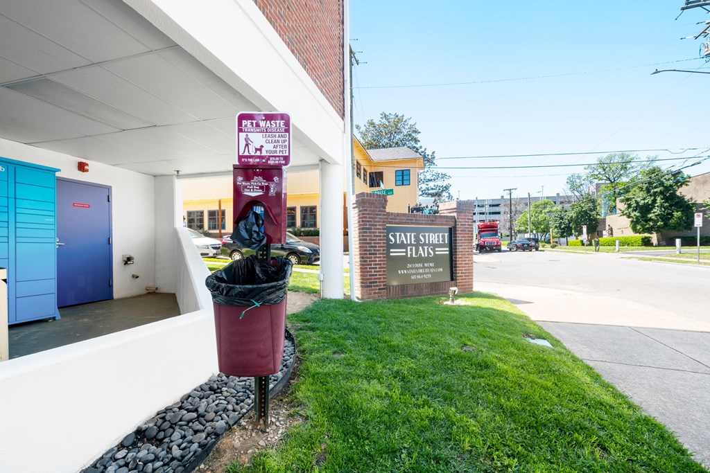 A sign for pet waste is on a pole next to a trash can at State Street Flats Apartments - pet friendly apartments in Nashville TN