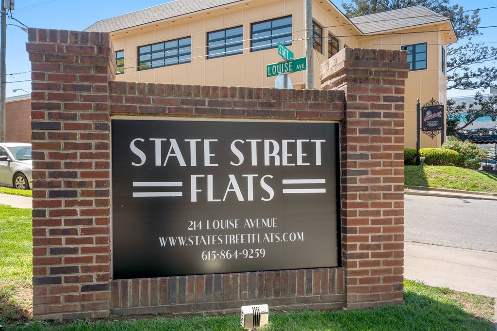 A sign for State Street Flats is displayed in front of a building.