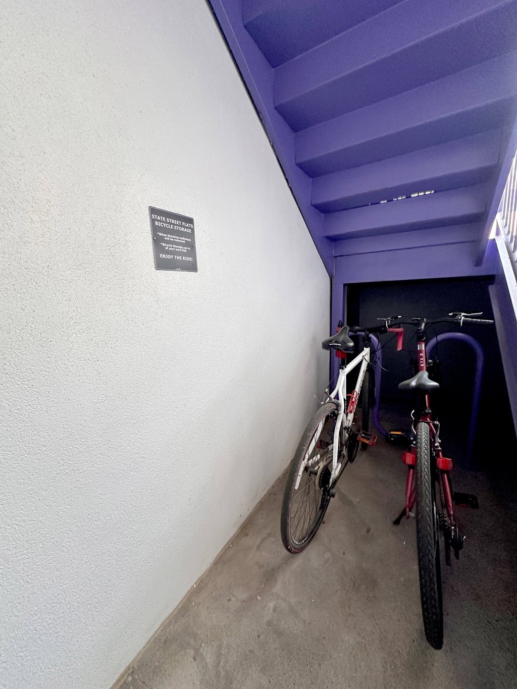 Two bikes are parked in a small bike rack area at State Street Flats Apartments.