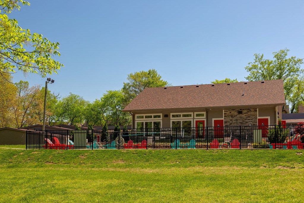 Community pool and pool house at the Retreat at Indian Lake apartments in hendersonville surrounded by black iron fence and lush green grass.