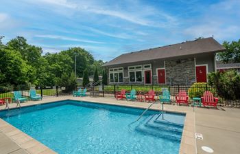 The Retreat at Indian Lake in Hendersonville TN swimming pool with red chairs and a building in the background.