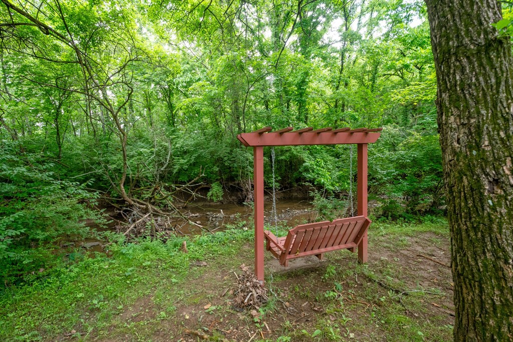 A wooden swing set is situated in a green forest at The Retreat at Indian Lake Apartments in Hendersonville TN.