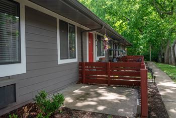 A grey apartment with a red door and a red bench outside at the Retreat at Indian Lake Apartments.