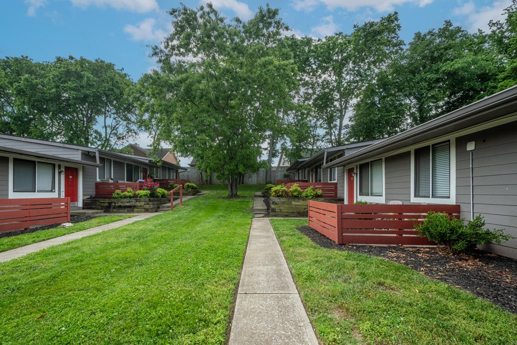 A row of studio and one bedroom apartments at The Retreat at Indian Lake with green lawns and trees in the background.