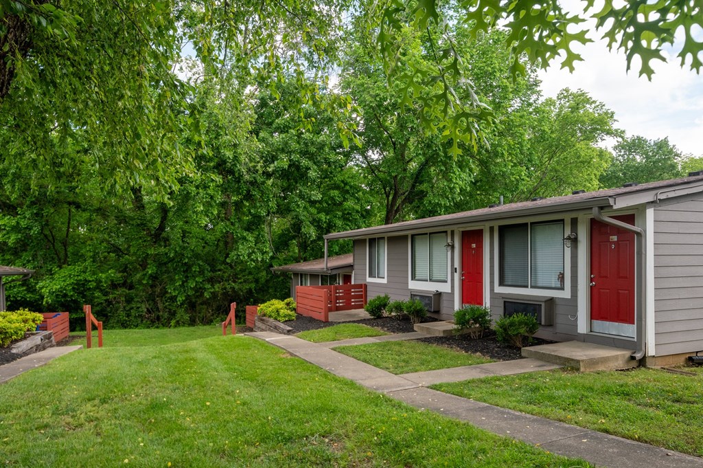 A row of studio and 1 bedroom apartments at The Retreat Apartments in Hendersonville with red doors and green trees in the background.