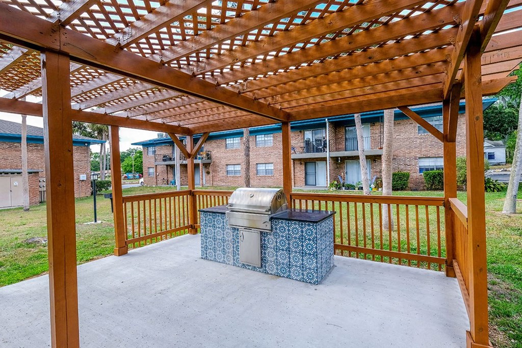 BBQ area at Watermarq Luxury Apartments in Lakeland, FL with stained wood trellis and large prep station with blue Spanish inspired tiles.