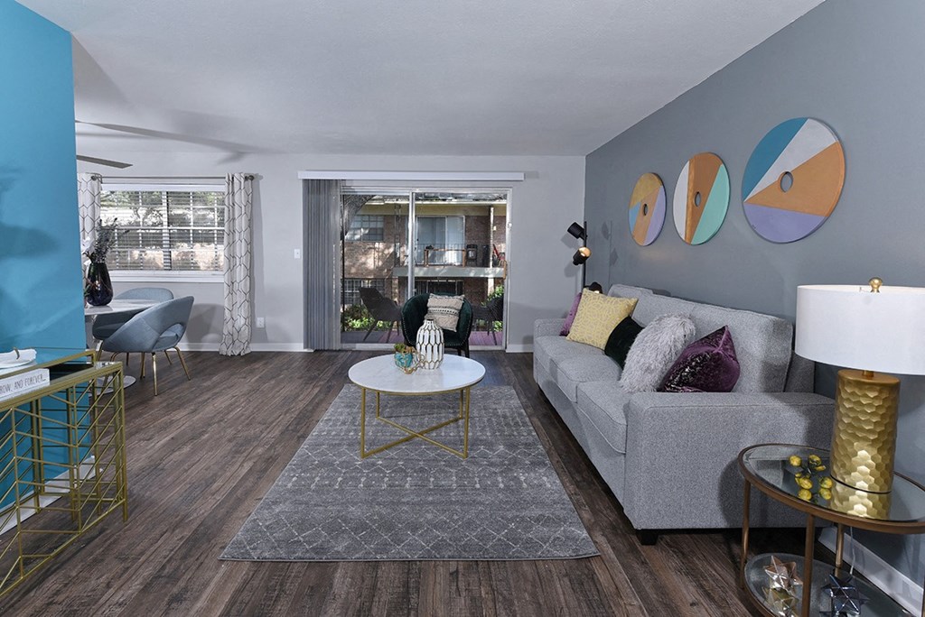 Open concept living room in Watermarc Lakeland apartments in lakeland, FL with sliding glass door to patio and modern decor.