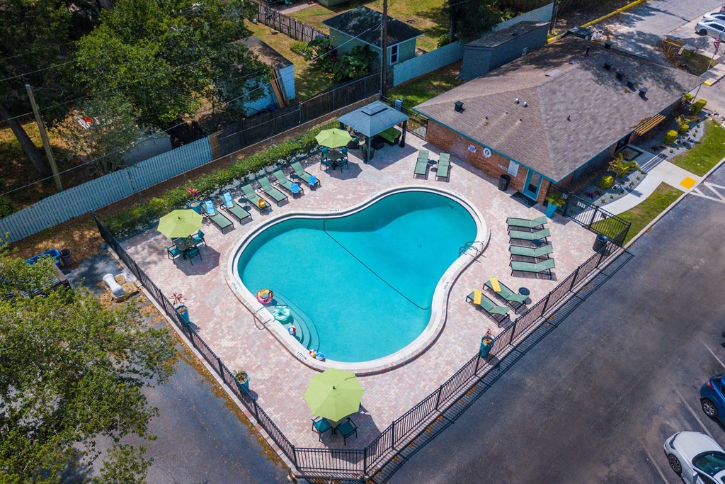 Pool at Watermarc Aerial view of community pool at Watermarc luxury Apartments in Lakeland, FL with large pool house and green lounge chairs with green umbrellas