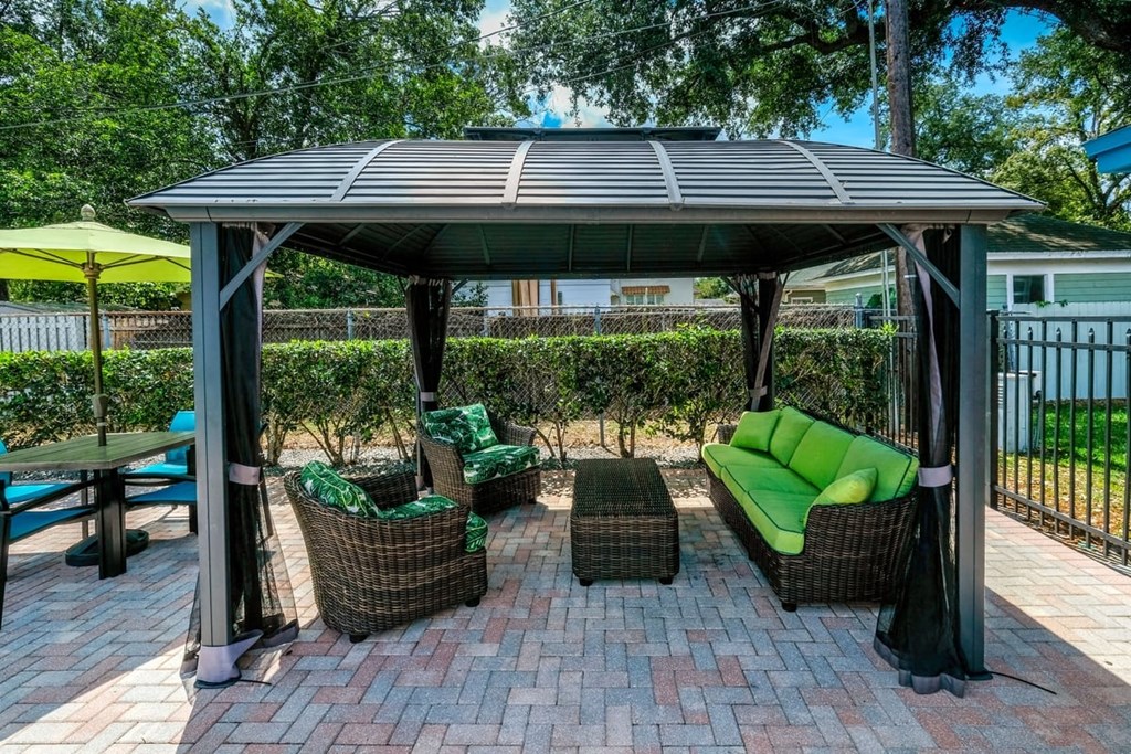 Poolside cabana at the Watermark Apartments in Lakeland, Fl with luxury wicker patio seating with green cushions under large shade with bug nets.