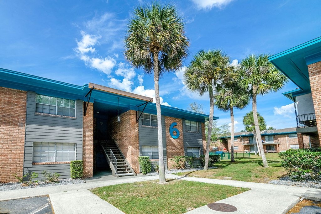 Exterior shot of Watermarc luxury Apartments in Lakeland, Fl. Buildings are brick with grey siding around windows, and front building has a large blue 6.