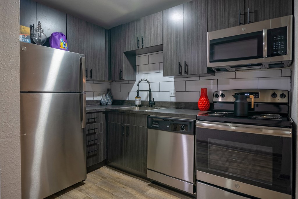 Kitchen in the Canvas Apartments in Nashville with stainless steel appliances and luxury grey wood cabinets that reach the ceiling.