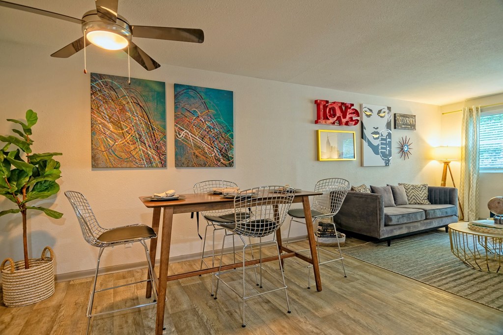 Open concept dining room and living room in the Canvas Apartments in Nashville with modern ceiling fan and modern four-seater bar-height table.