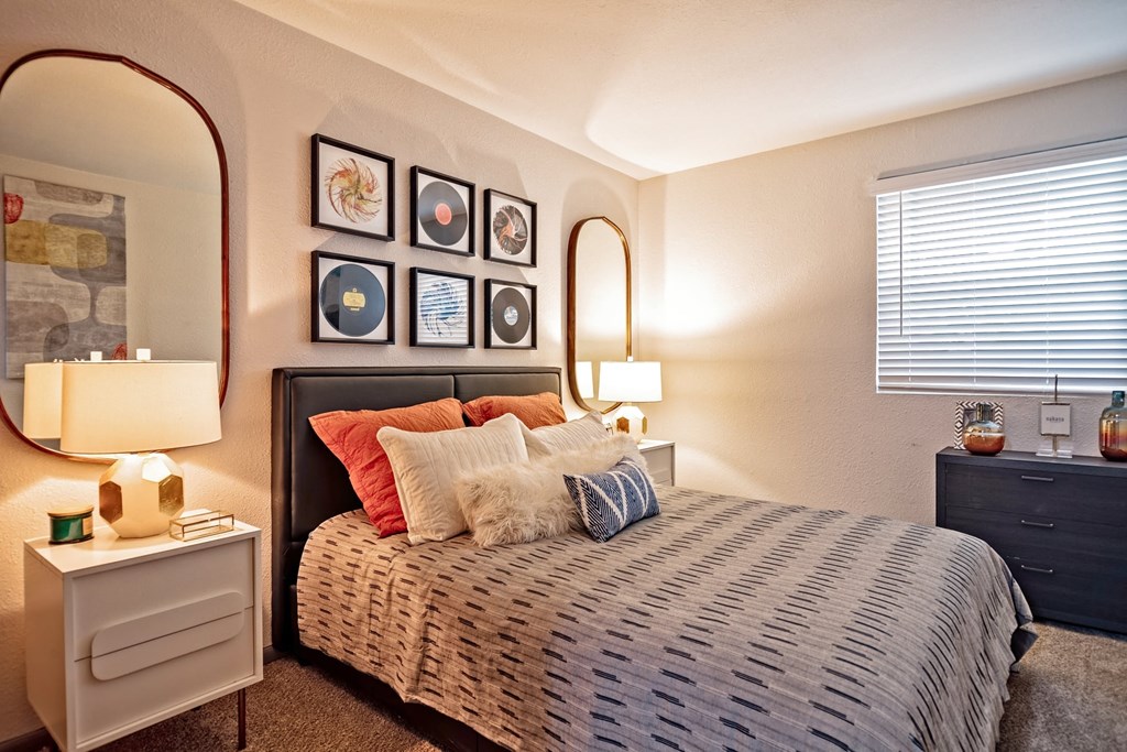 Large bedroom in the Canvas Apartments in Nashville with large bed, midcentury modern nightstands and mirrors, and luxury carpet.