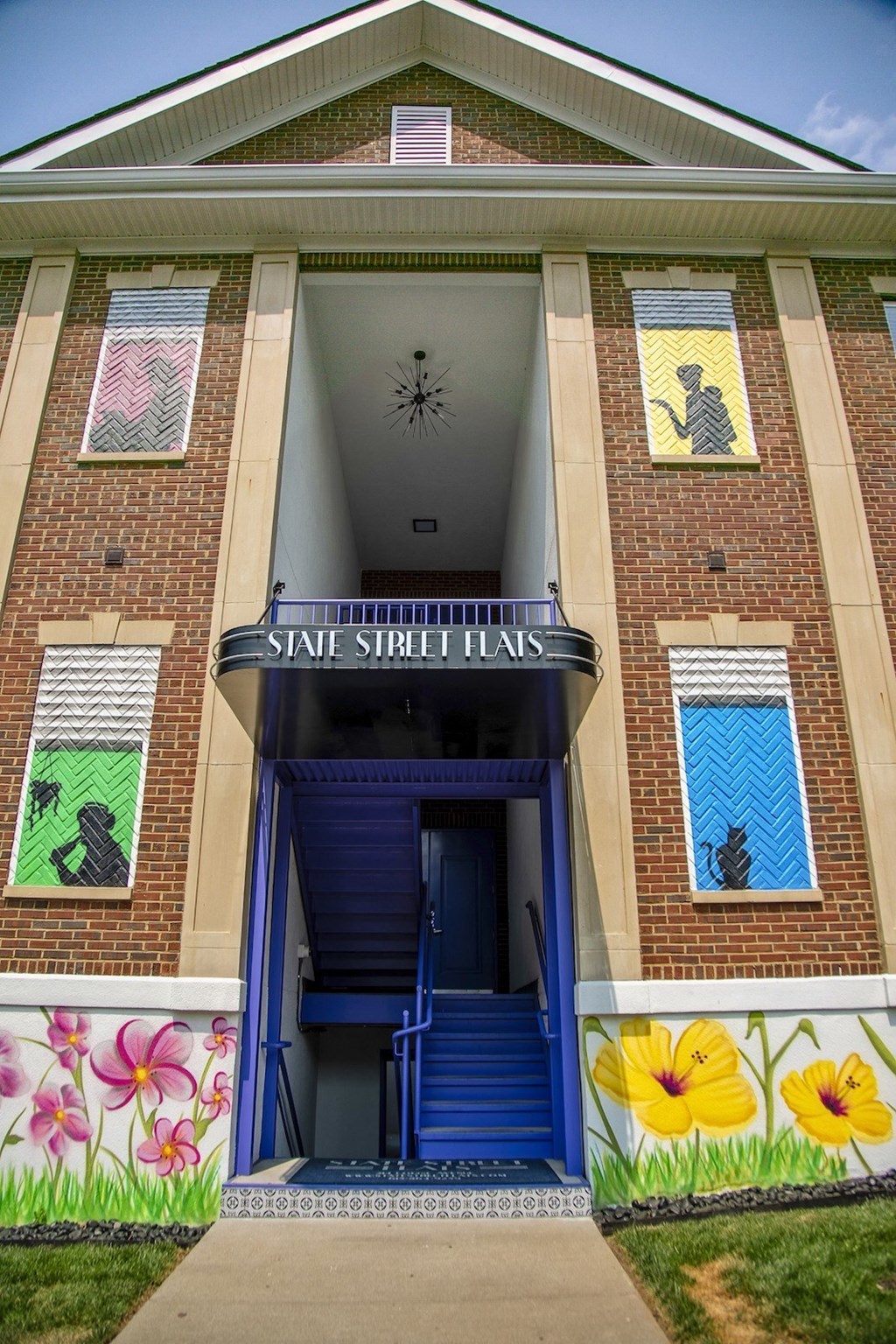 Entrance to State Street Flats apartment building in downtown Nashville. Building is red brick with colorful painted windows and wainscoting.