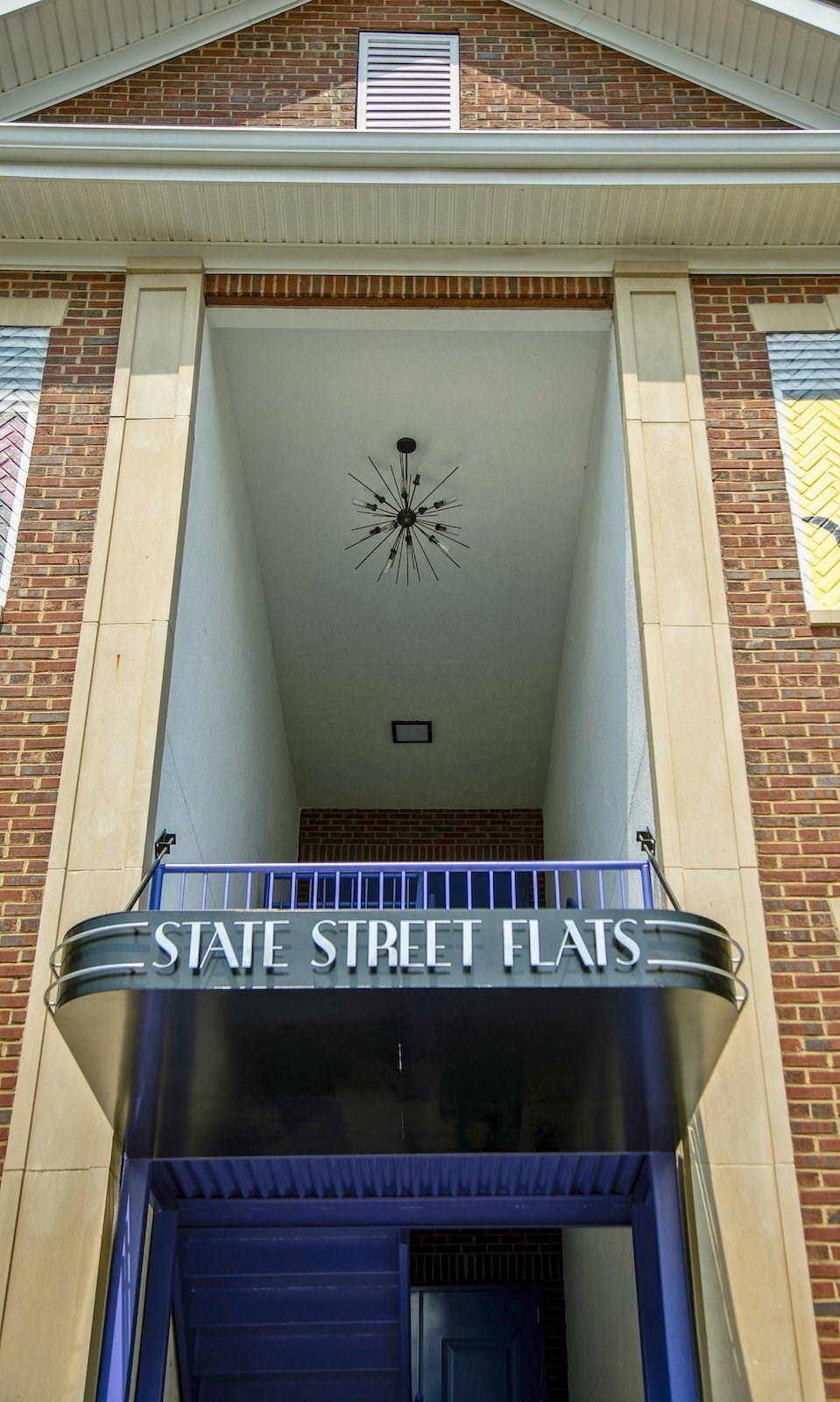 Entrance to State Street Flats apartment building in downtown Nashville with art deco sign and blue staircase and balcony.