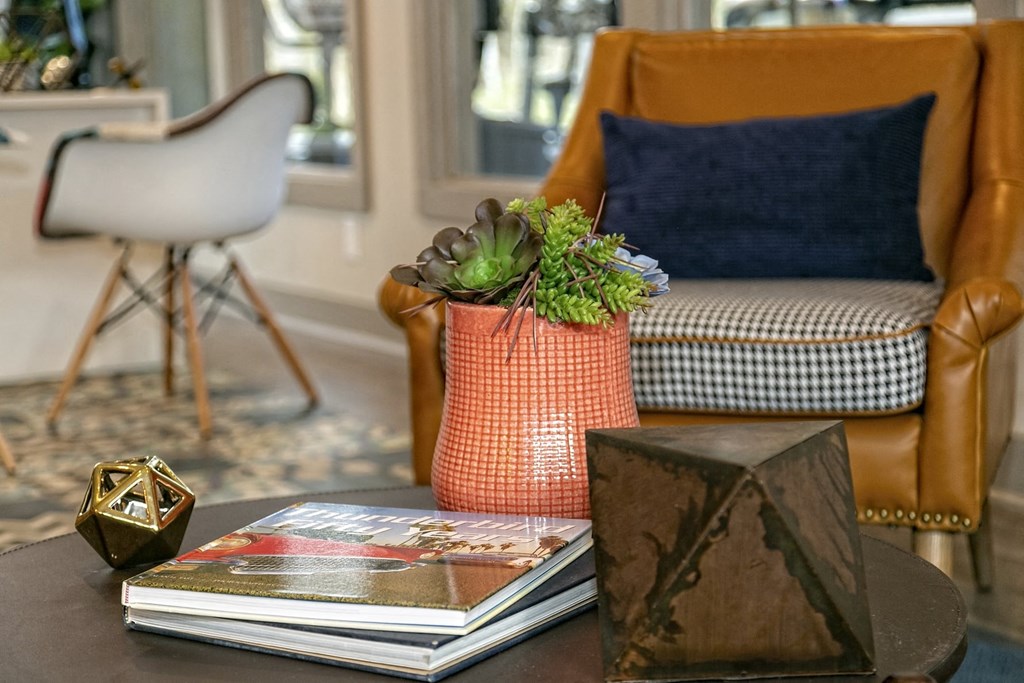 The Retreat at Indian Lake apartments lobby sitting area with mid-century modern chair next to coffee table with succulent arrangement.