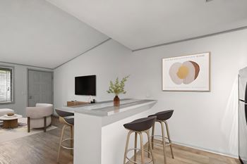 A modern kitchen with a breakfast bar area and a framed artwork on the wall at The Retreat at Indian Lake Apartments.
