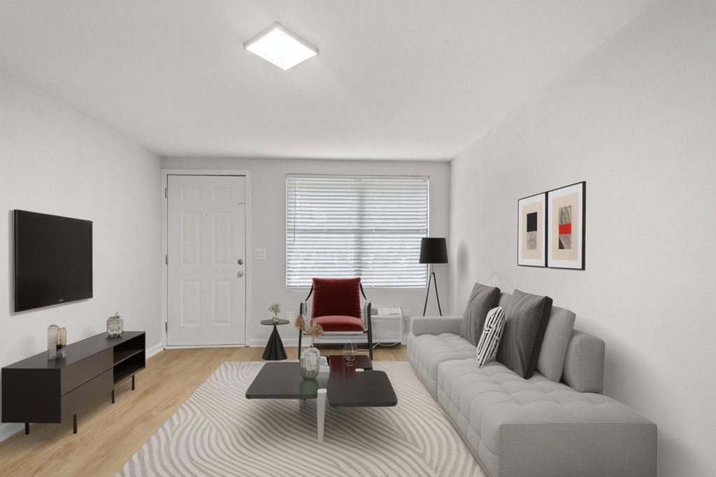 Retreat at Indian Lake apartments in Hendersonville, TN living room with a grey sofa, a red chair, a black table, and a white door.
