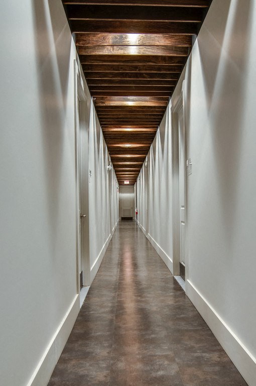 Interior hallway in State Street Flats apartment building in Nashville with concrete tile floors, white walls, and stained wood ceiling beams.