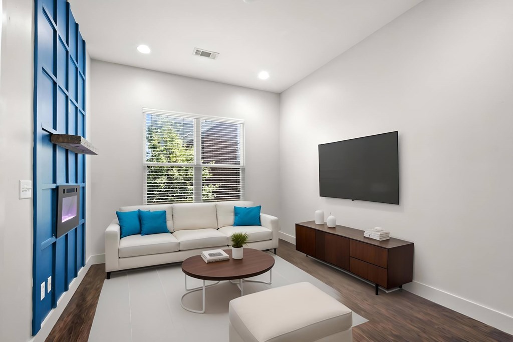State Street Flats 1 bedroom apartments Nashville modern living room with a white couch, a brown coffee table, an electric fireplace, and a flat-screen TV mounted on the wall.