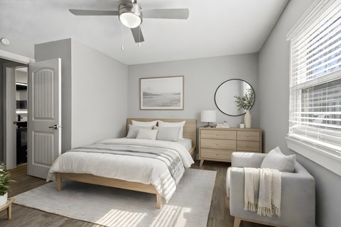 A bedroom with a bed, dresser, and chair at Mandarin Bay Apartments.