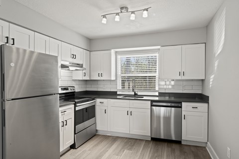 A kitchen with white cabinets and a stainless steel refrigerator at Mandarin Bay Apartments.
