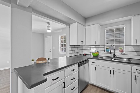 A modern kitchen with white cabinets and a black countertop at Watermarc one and two bedroom apartments in Lakeland, FL.