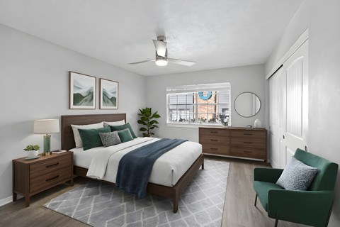 A bedroom with a bed, nightstand, and chair at Watermarc Apartments.