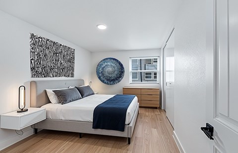 The Canvas Apartments bedroom with a bed, nightstand, and artwork on the wall.