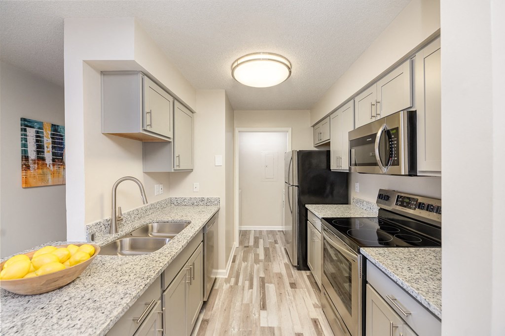 A kitchen equipped with stainless steel appliances, granite countertops, and hardwood-style flooring.