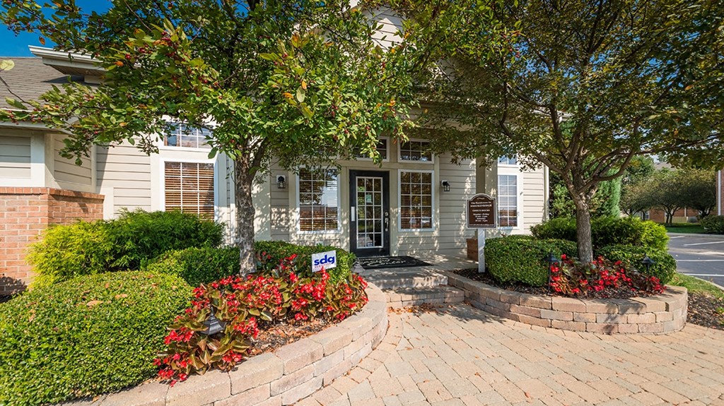 a house with a brick walkway and trees in front of it