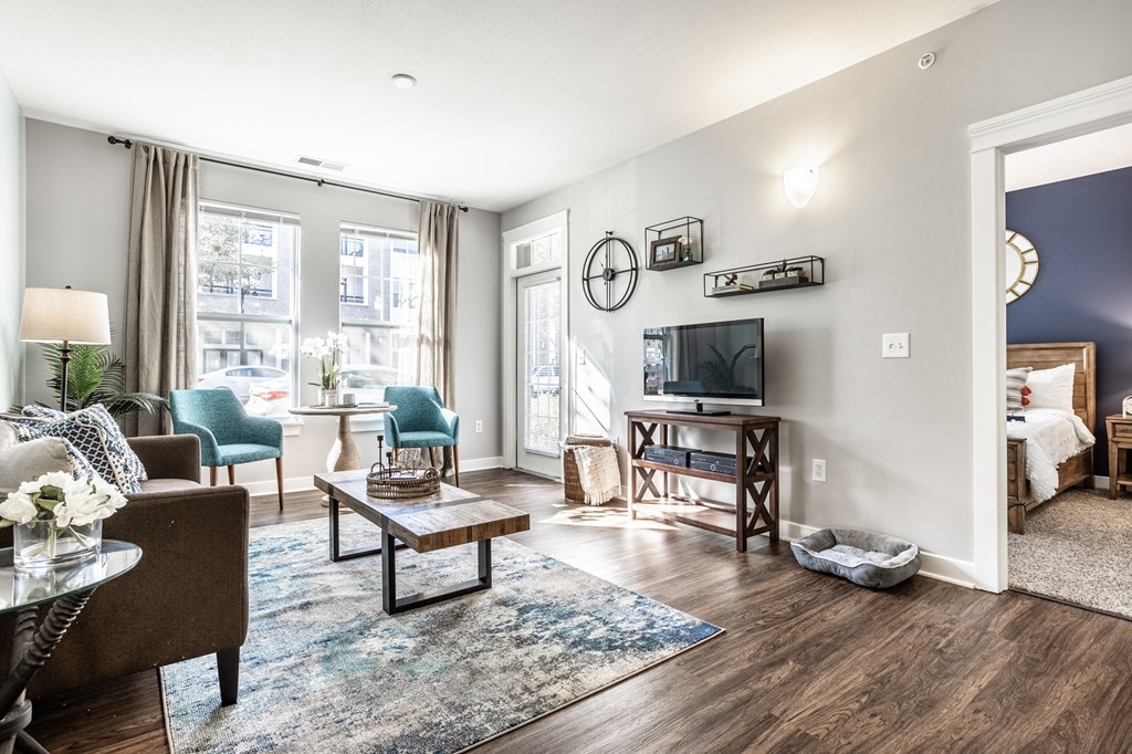 a living room with a large window and a door that leads to a bedroom