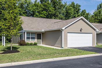 A house with a garage door and a tree in front.