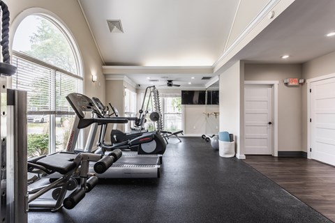 A fitness center equipped with a selection of workout equipment and large windows.