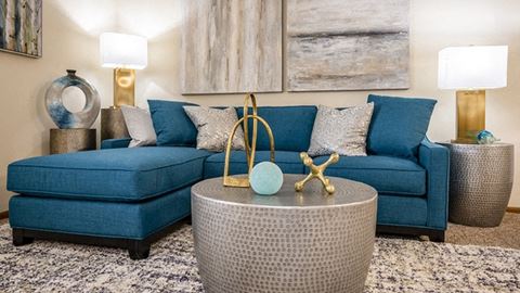 a living room with a blue couch and rattan coffee table