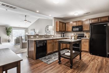 A kitchen with wooden cabinets and a black refrigerator.