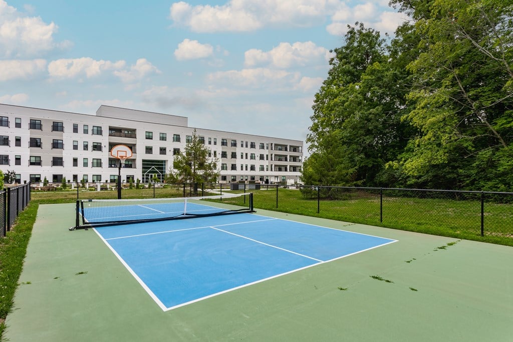 Altura Tennis & Pickle Ball Court A blue tennis court in front of a white building.