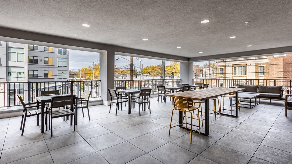 An outdoor sky lounge with tables, chairs, and a couch at Madamore.