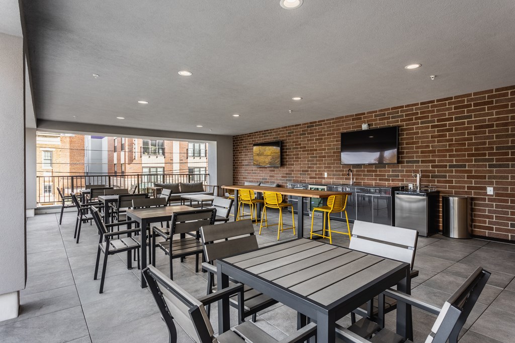 A private sky lounge at Madamore with tables and chairs, a brick wall, and two TV's.