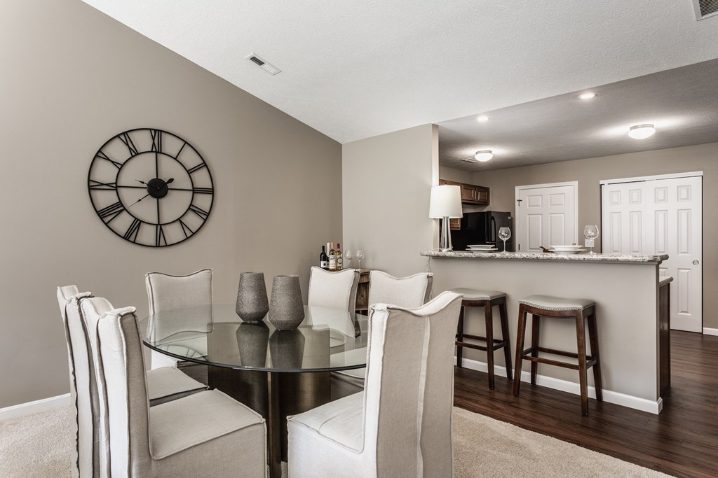 Wheaton Ridge dining room table surrounded by six chairs, next to a. kitchen.