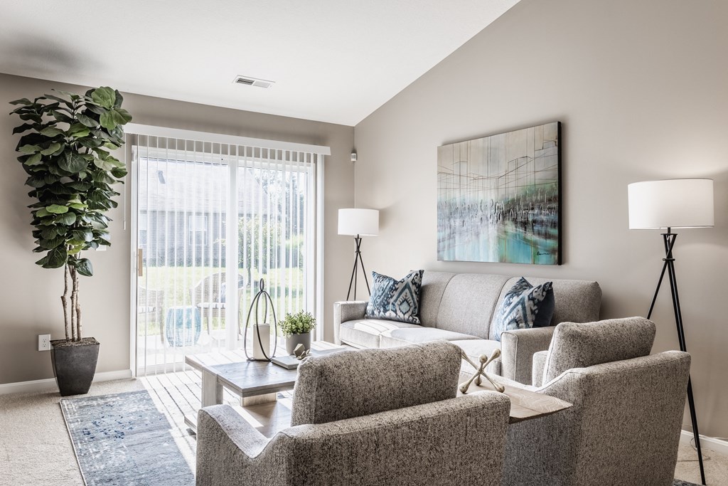 a living room with a couch chairs and a coffee table in front of a sliding glass door