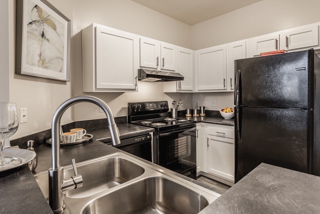 a kitchen with white cabinets and black appliances
