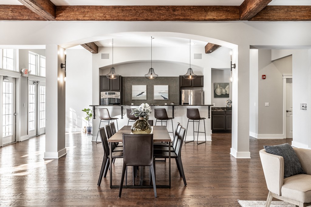 a dining area with a wooden table and chairs and a kitchen in the background