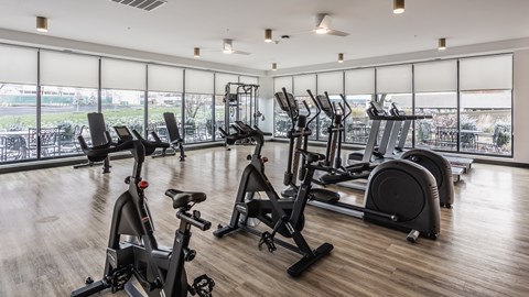 A fitness center at Altura Apartments provides residents with a row of treadmills for running and elliptical machines for low-impact exercise.