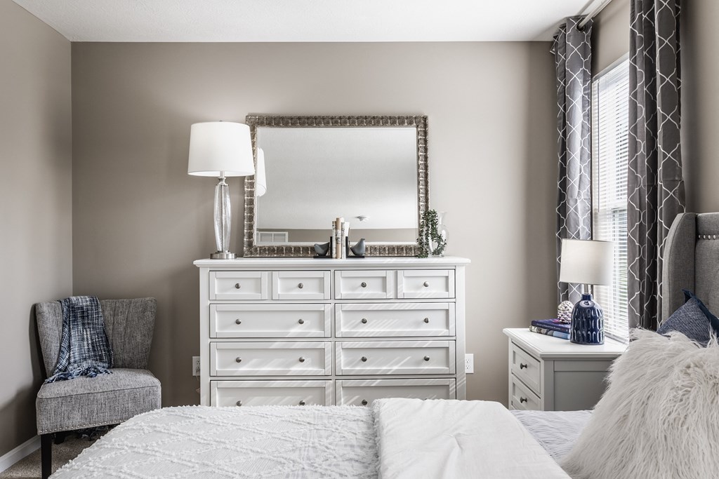 Spacious bedroom with a large dresser and mirror, perfect for personal touches